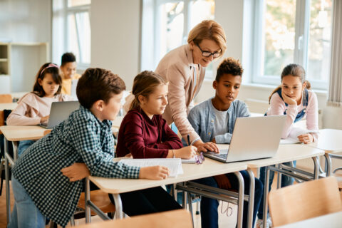 Groupe d'enfant utilisant un ordinateur portable avec leur professeure