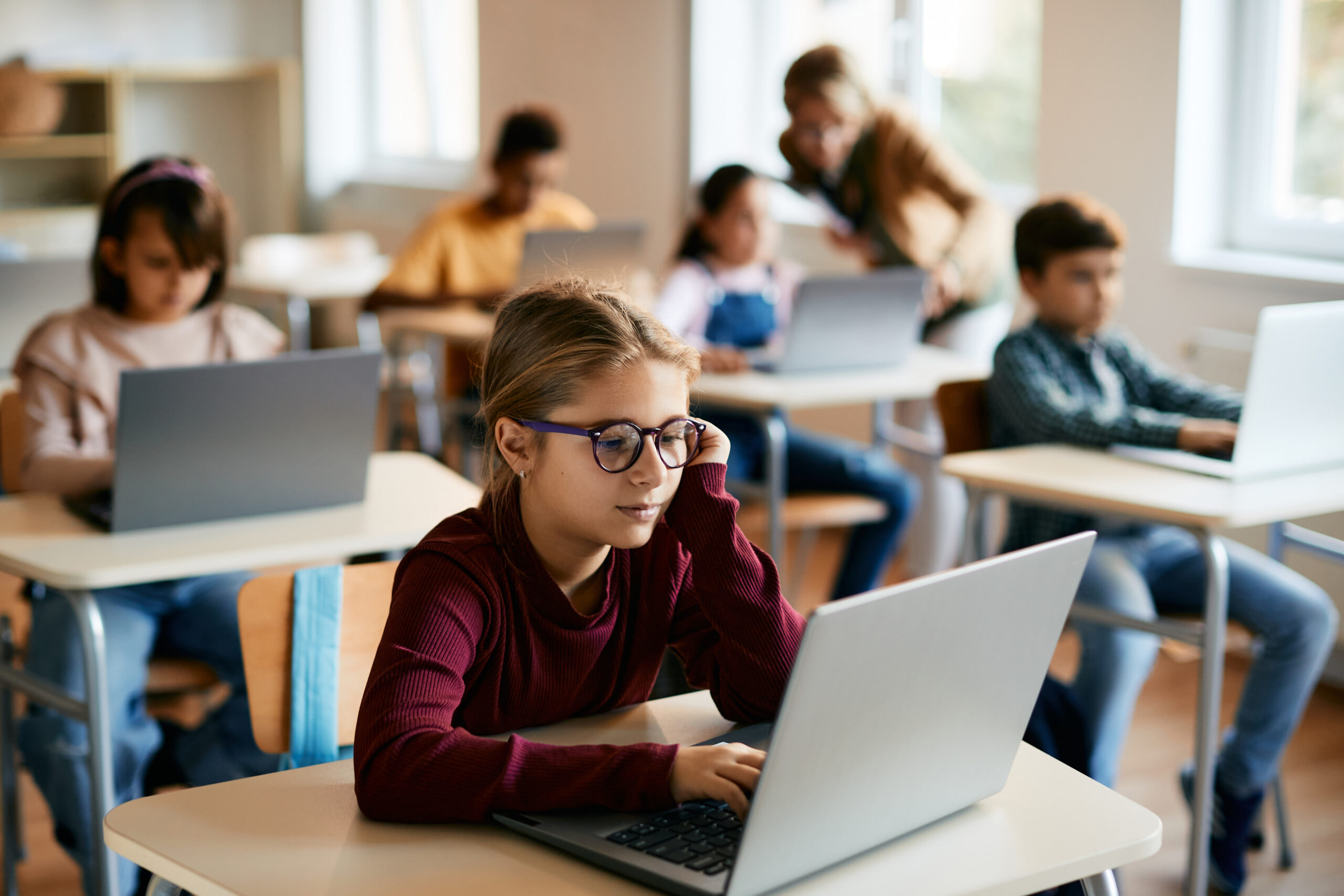 Élève en primaire travaillant sur un ordinateur portable dans une salle de classe numérique