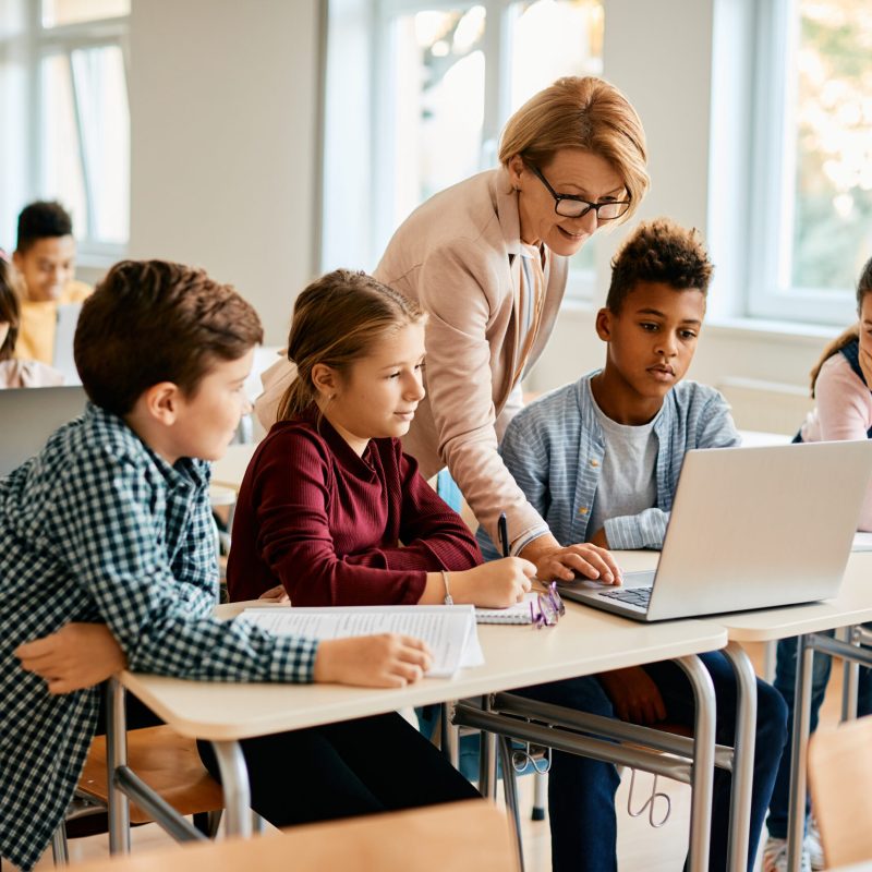 Groupe d'enfant utilisant un ordinateur portable avec leur professeure